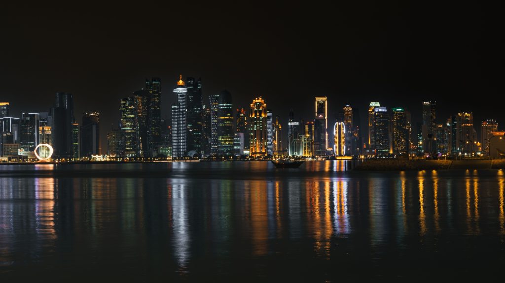 Doha skyline at night with reflections on water.