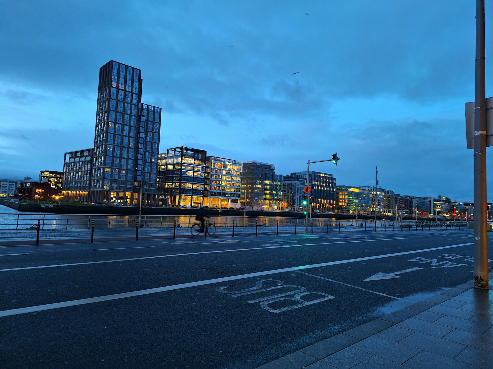 a city street at dusk with a large building in the background