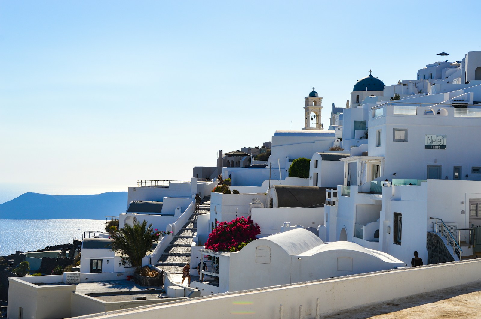 a white building with a steeple next to a body of water